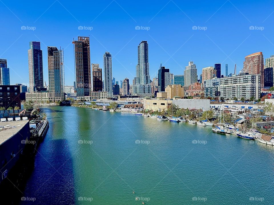 This is „Newtown Creek“ seen from the „Pulaski Bridge“ that connects LIC, Queens to „Greenpoint“, Brooklyn. Straight ahead in the distance you can see the „Manhattan“ skyline. 2023. Hypnotic Productions