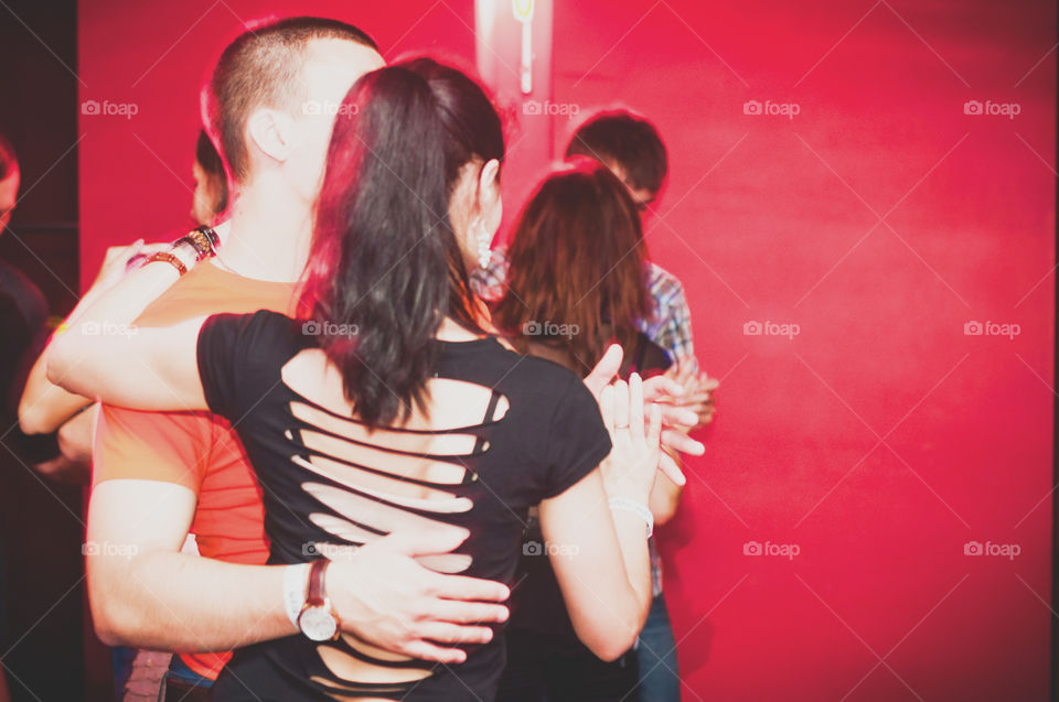 Couple dancing in the room with red walls 