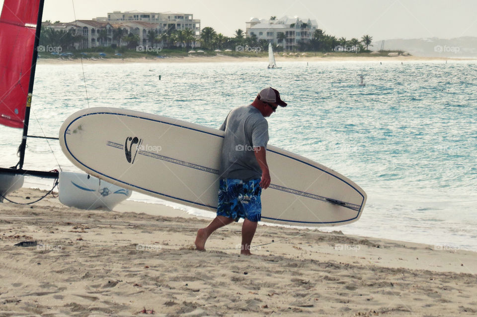 A surfer walks from the Beach to the ocean