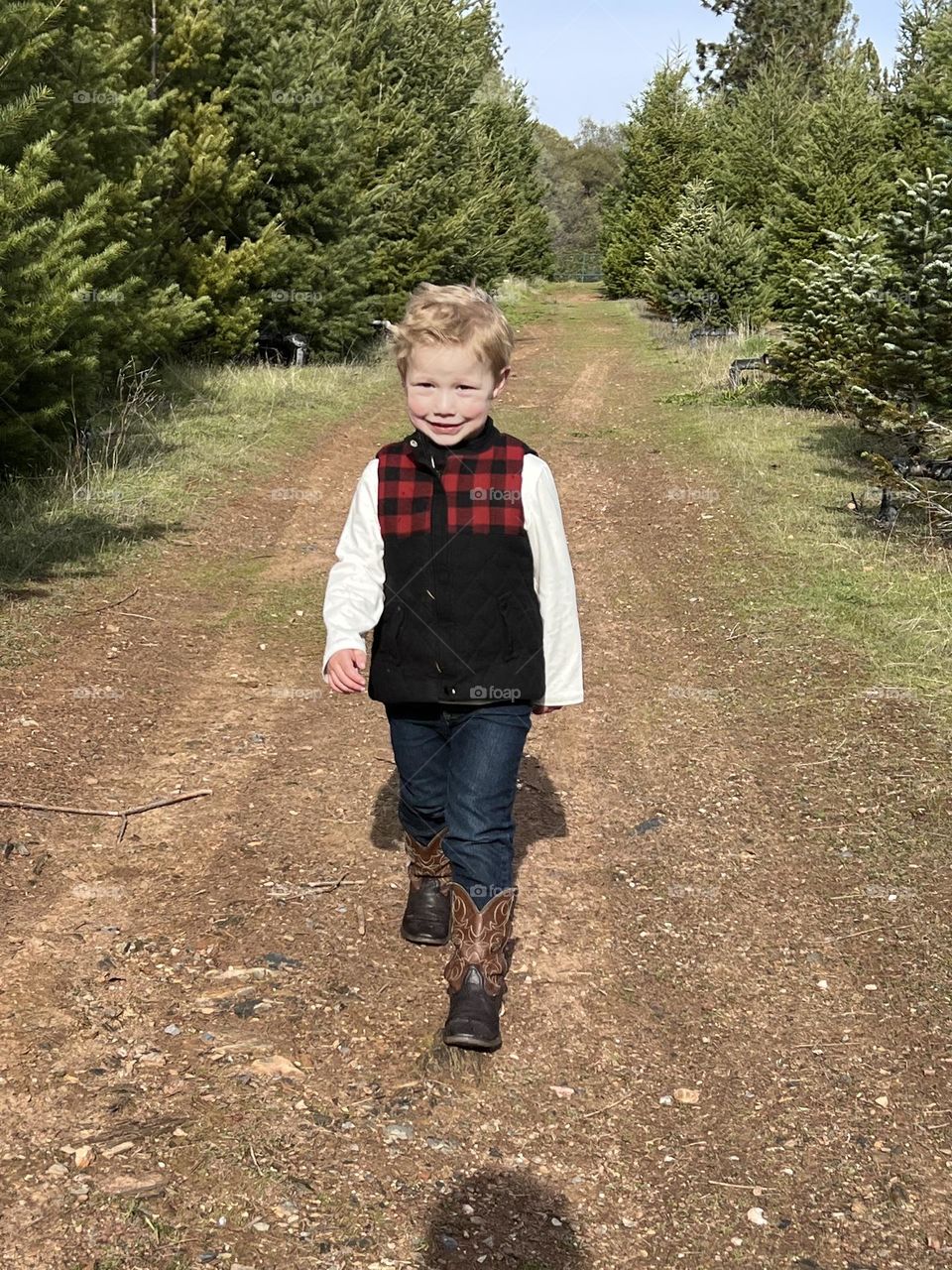 Boy waking spotting his plaid vest and cowboy boots 