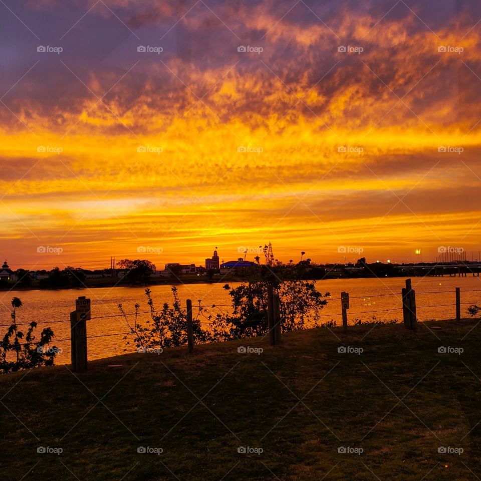 A beautiful orange glow signals the end of the day as the sunset is reflected on the Arkansas River in Oklahoma