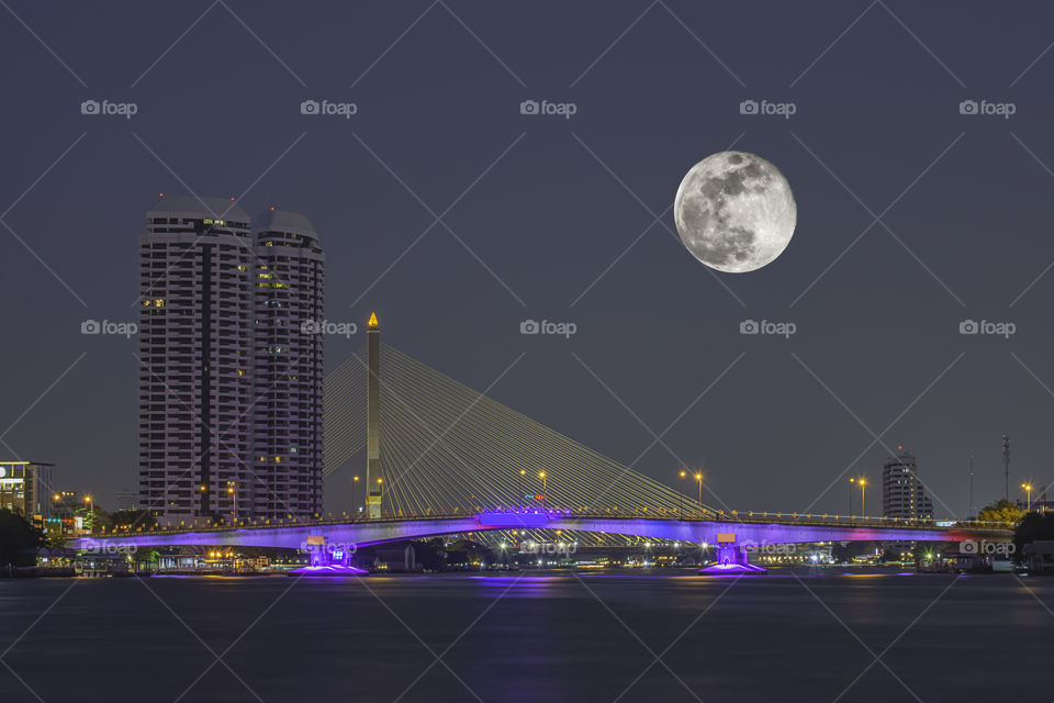 Full moon In the dark sky and The Beauty Of The Chao Phraya River and the lights of the car on Pinklao bridge at Night , Bangkok in Thailand.