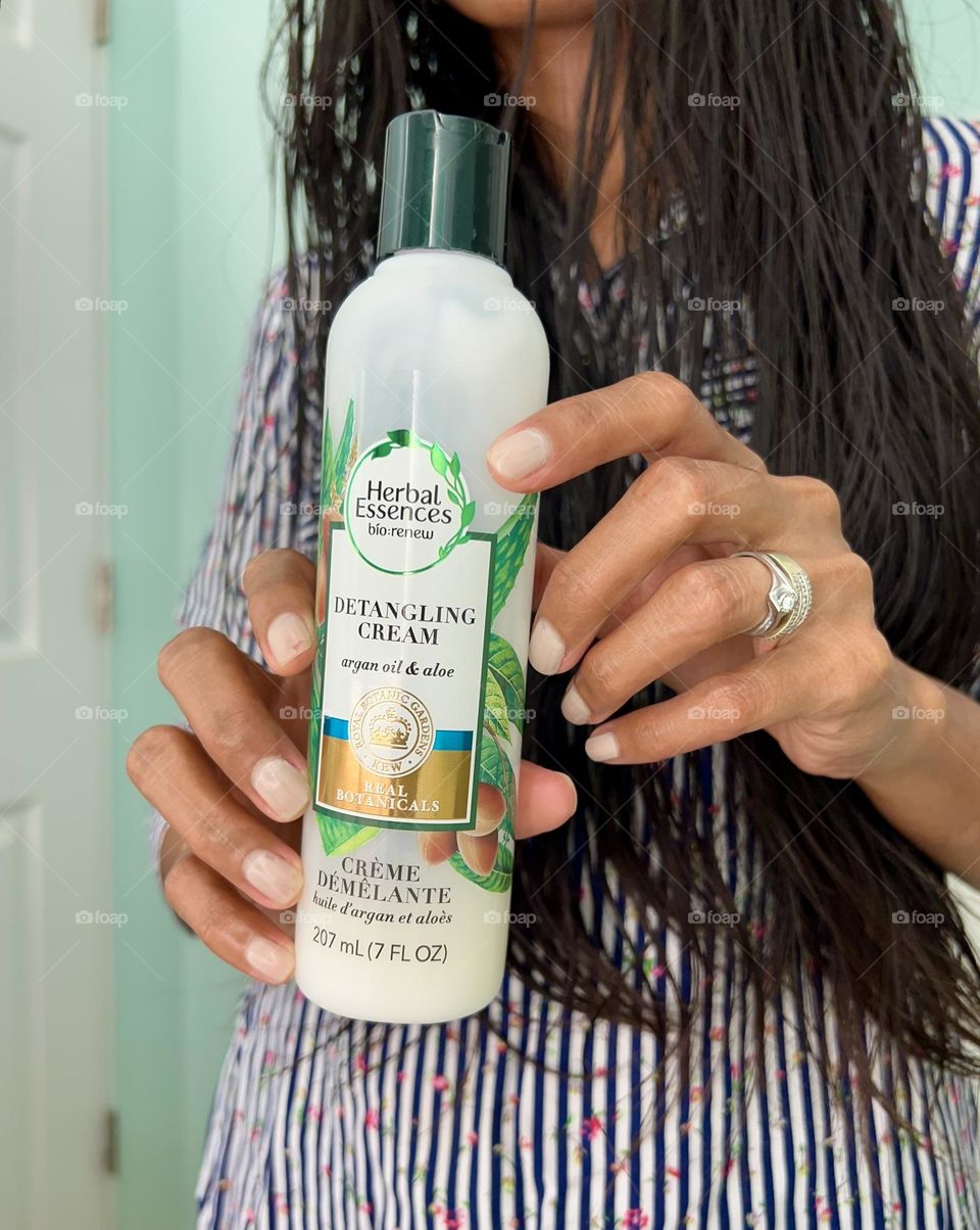  A woman holding a Herbal essences detangling cream