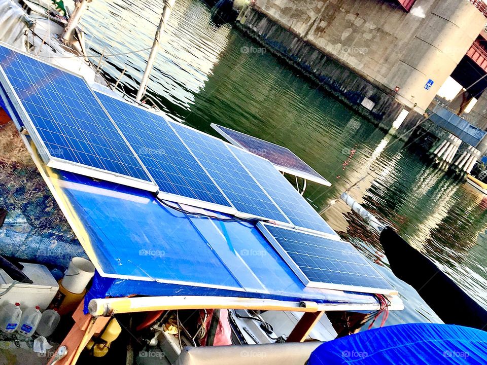 Solar panels arranged in two rows on the roof of our houseboat “Salvation” at Newtown Creek in LIC, Queens, NY harness the sun’s energy during the day. It is stored on several deep cycle batteries. 2021. Hypnotic Productions