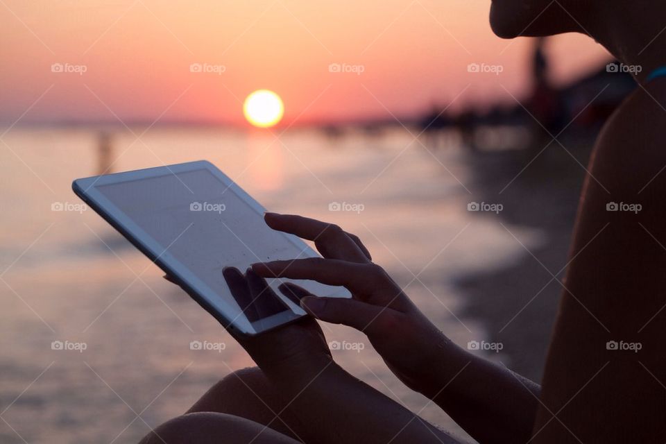 Woman by the sea and working on a tablet