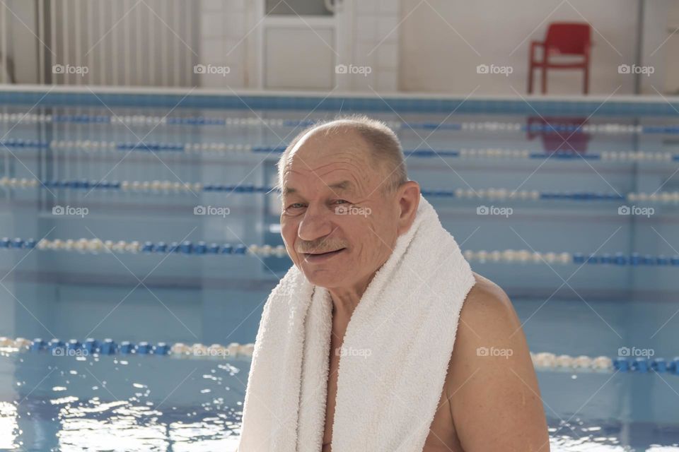 A happy, elderly man is relaxing on vacation in the pool, playing sports and leading an active and healthy lifestyle.