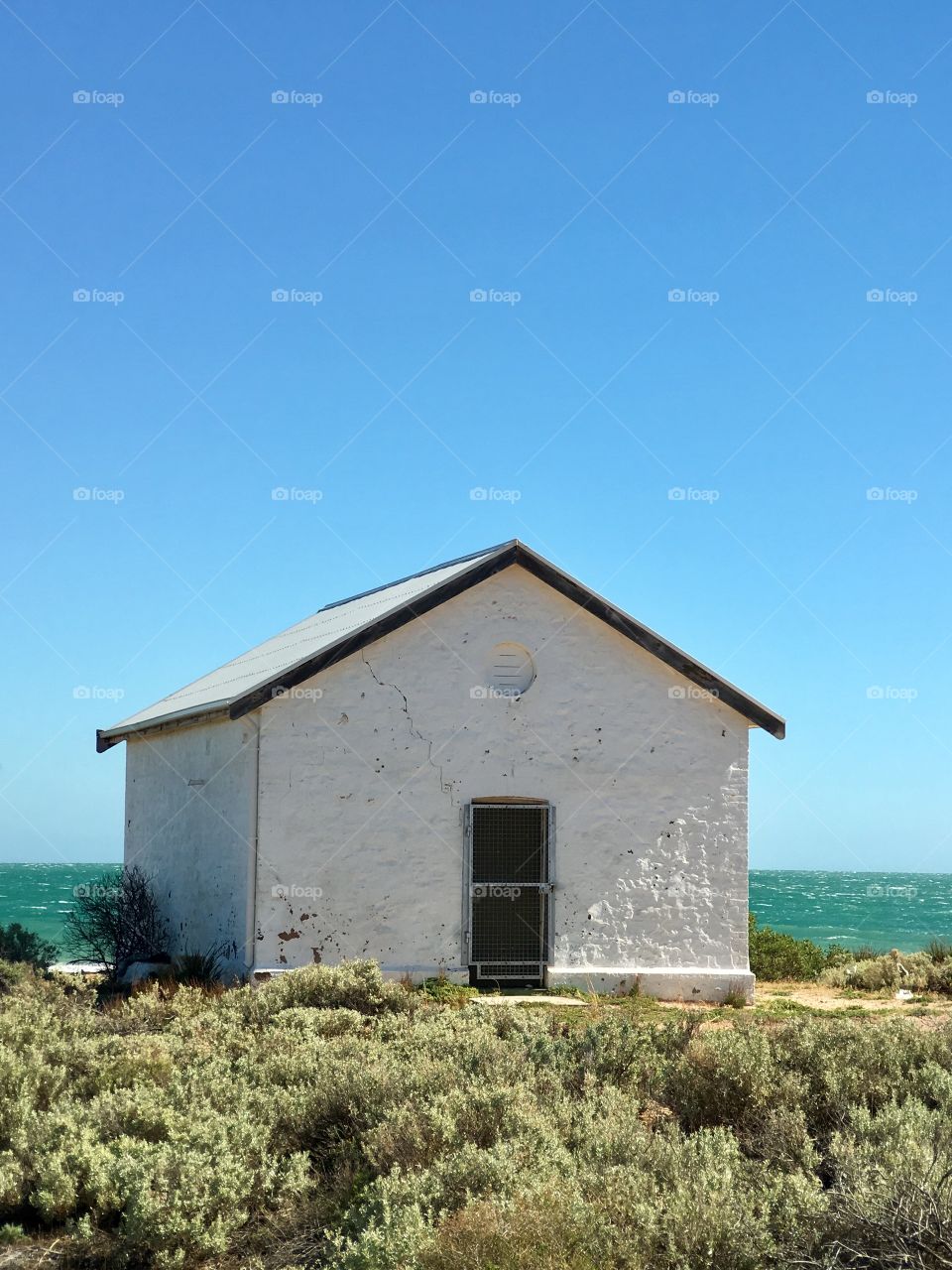 Sweet, simple, white stone lighthouse keepers cottage home Oceanside  heritage building south Australia 