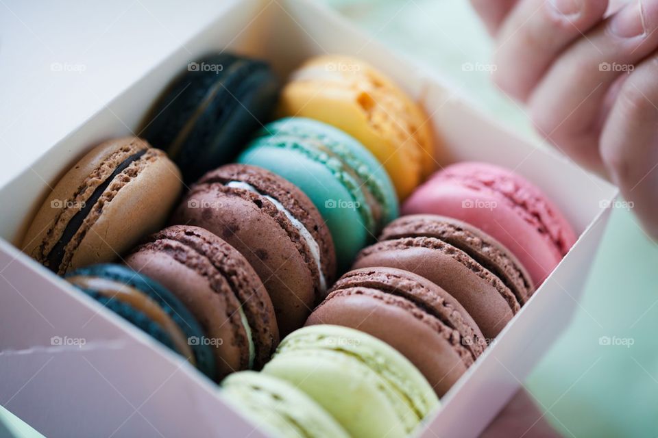 Human's hand holding multi colored macaroons