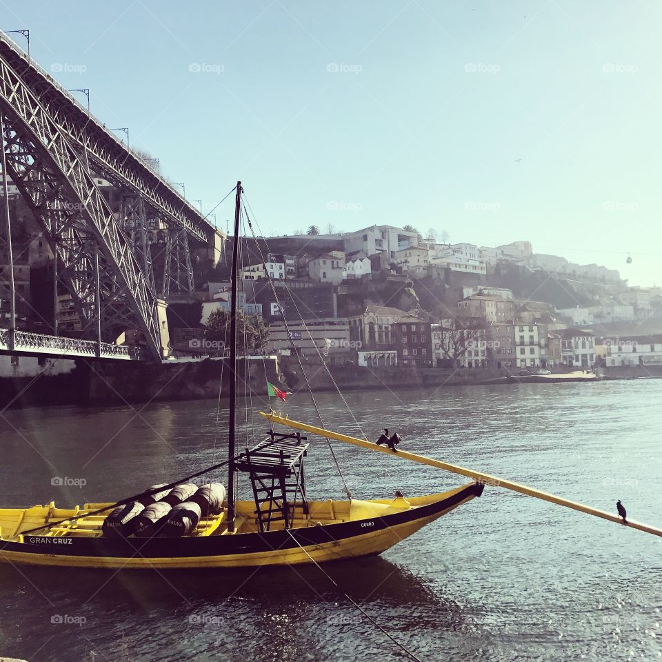 Yellow sail boat on the water with the city of Porto behind on a hill in Portugal