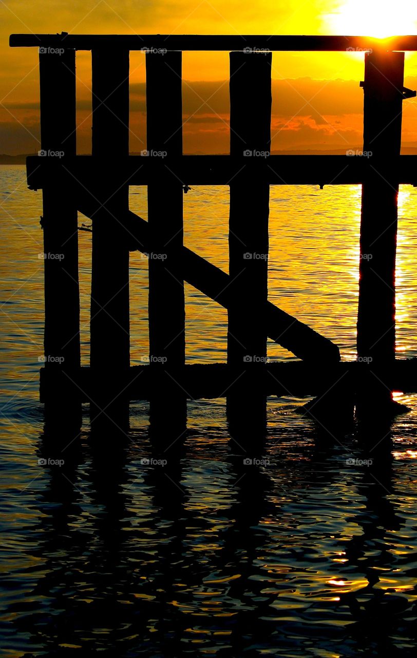 Sunset Gate. Wooden structures at the entrance to Grantob harbour, Scotland.