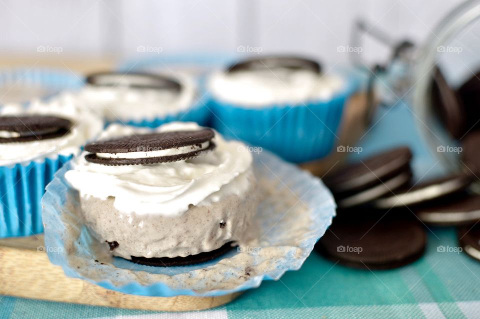 Oreo cookie ice cream cupcakes on a wooden board and white and blue background 