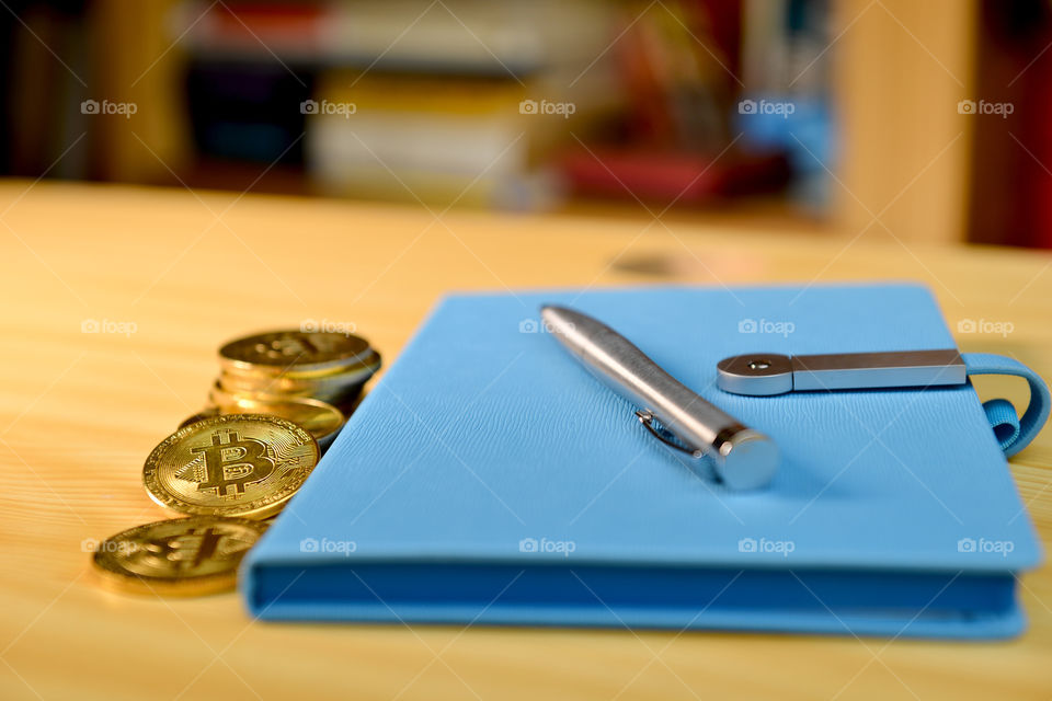 on the table golden cryptocurrency coins, blue notebook with pen