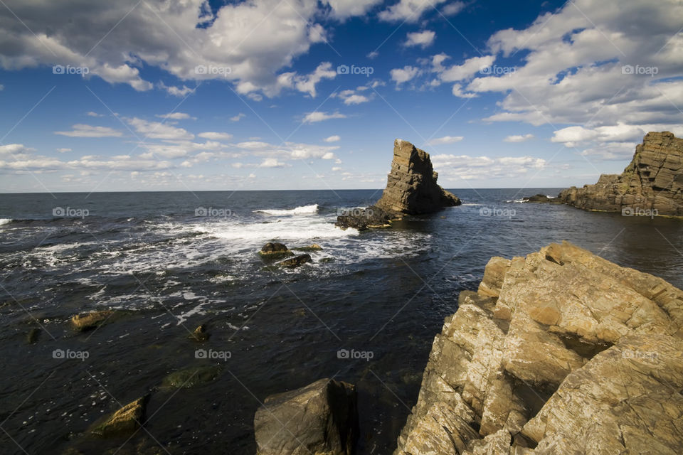 lonely rock in the white clouds and blue bay