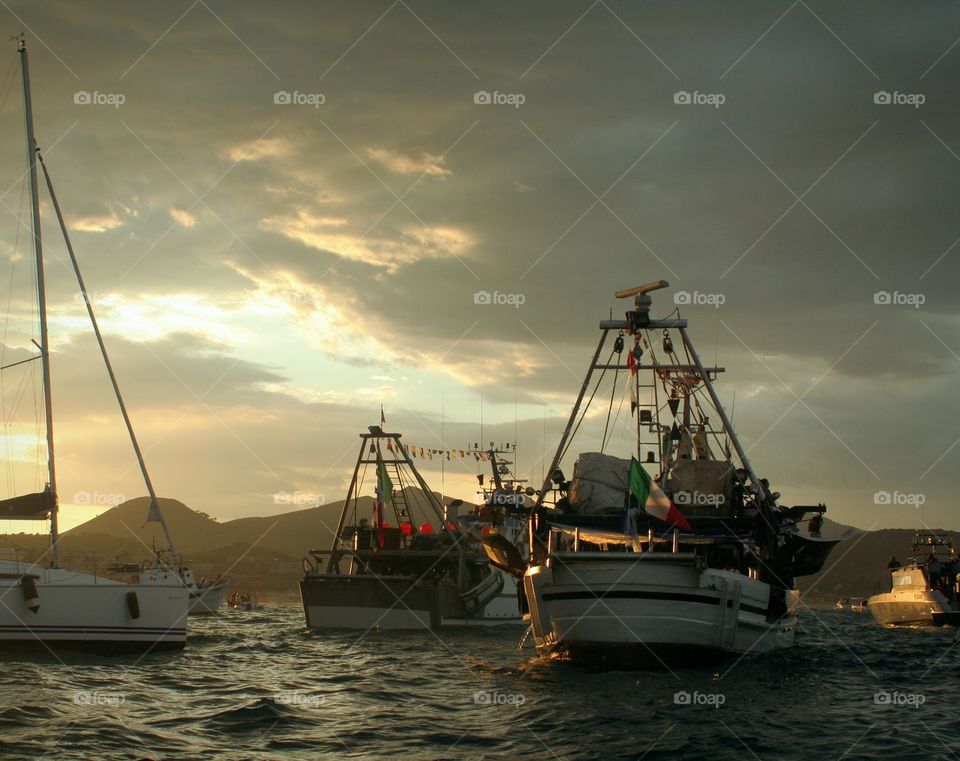 Waving flags decorating various boats during navigation near the coast.