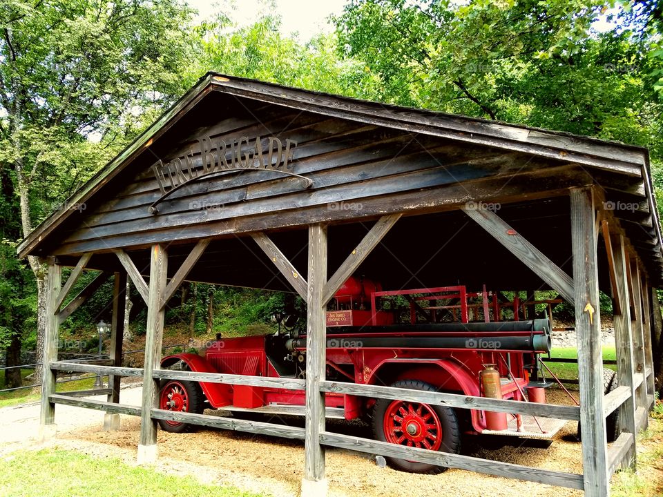 Vintage Red Fire Engine under wooden roof in forest