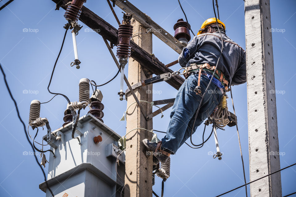 Electrician working on the electricity pole to replace the electrical insulator