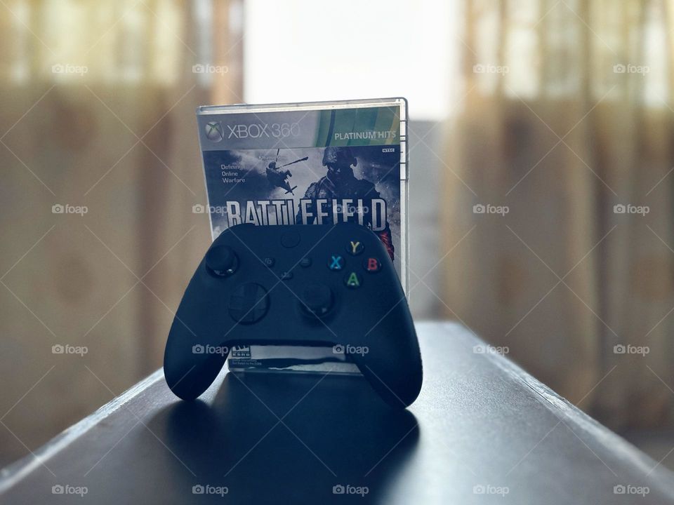 Battlefield video game box behind of a Xbox controller with natural light at the background.