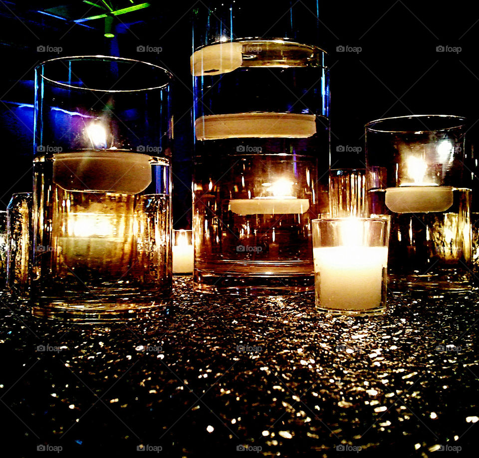 Candle Lit Glitter Glass. A nicely arranged set of glass cups on top of glitter on a table at a wedding.