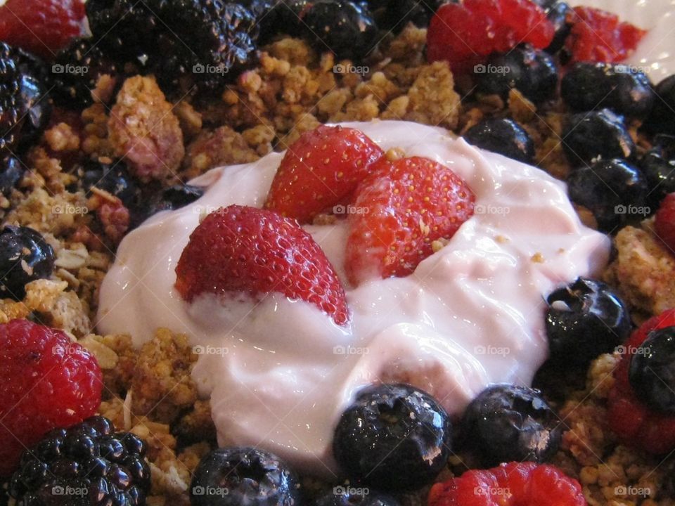 strawberries and yogurt and granola with raspberries blackberries and blueberries
