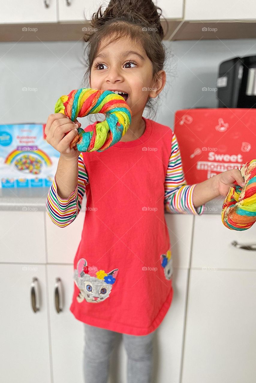 Child eats colorful bagel, eating rainbow bagels, child bakes bagels with mother, making rainbow bagels 