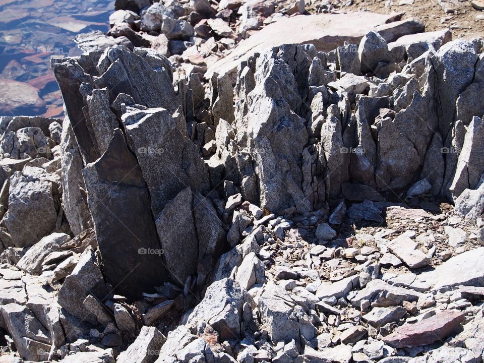 Jagged rocks and boulders along the shoreline of Ochoco Lake in Central Oregon on a sunny spring day.