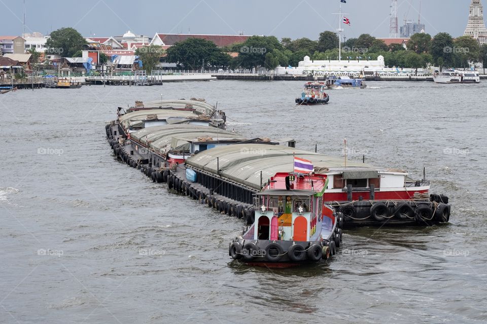 Small boat pull and push a bigger boat in Chao Phraya river , Bangkok Thailand