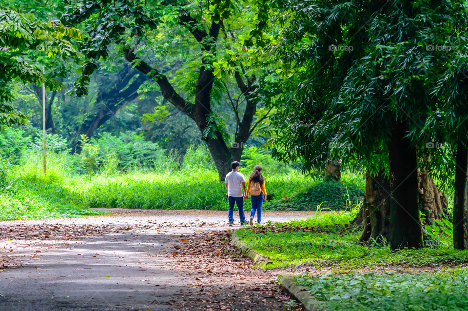 Portrait of two joyful young loving Couple walking in a green autumn park on a romantic summer day. Pre-wedding marriage engagement concept. Togetherness composition. Botanical garden, Kolkata, India