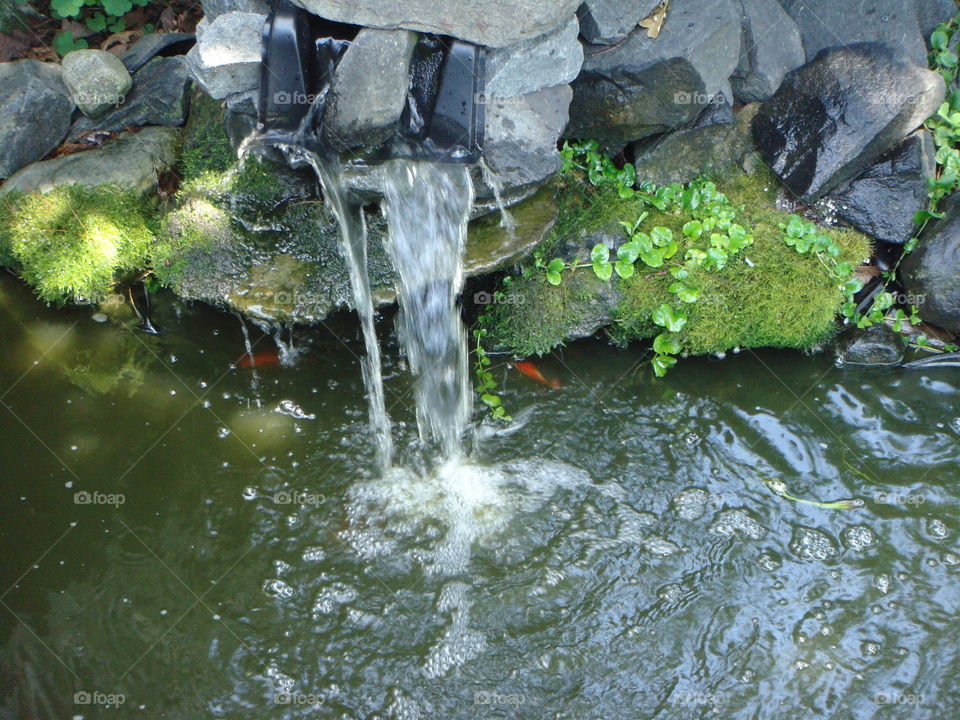 Waterfall over rocks into pond.