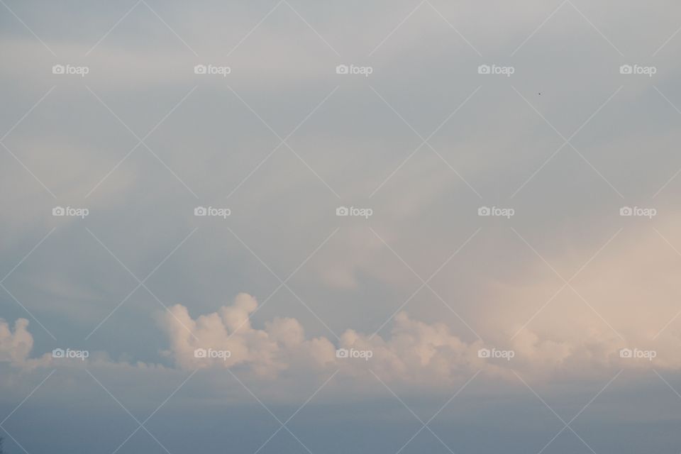 Cumulonimbus clouds in a pale blue sky low on the horizon before a storm rolls in