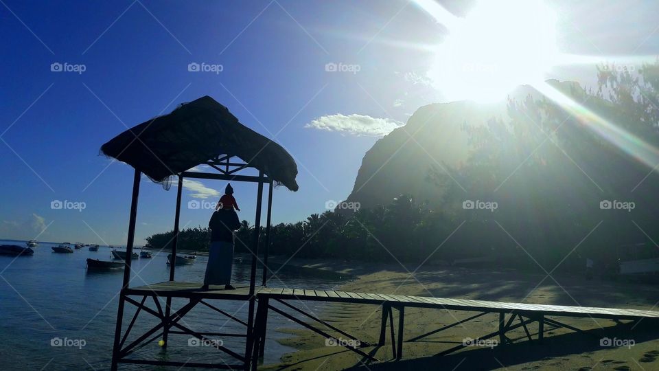 sun mountain sea father daughter beach boats tropics Mauritius island shiny blue sky morning