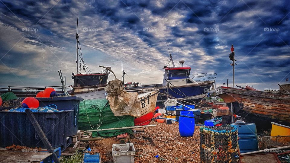 Beached fishing boats on shingle on a bright cloudy day
