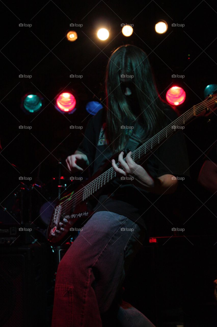 Bass player rocking out on stage. Bass guitar player rocking out with stage lighting effects 