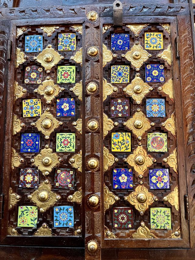 Old wooden door carved and decorated in multicolored oriental style