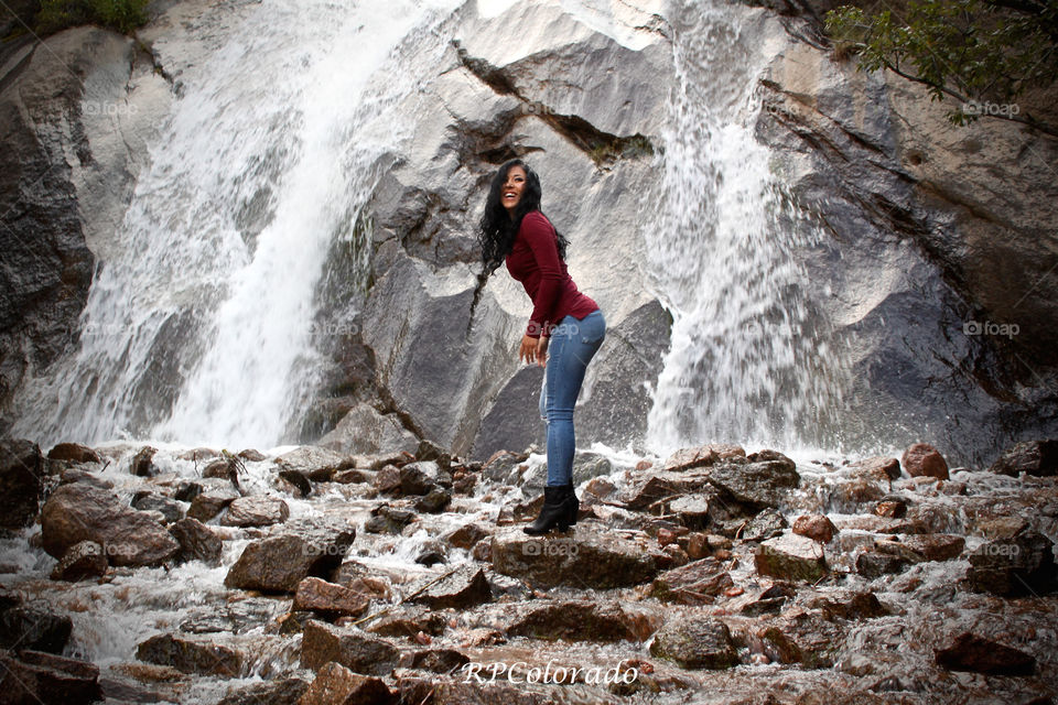 Smiling woman standing near waterfall
