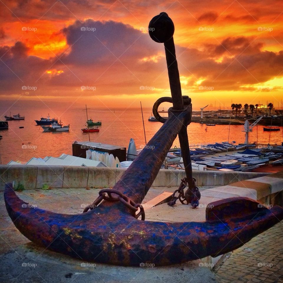 Rusty anchor at harbor during sunset
