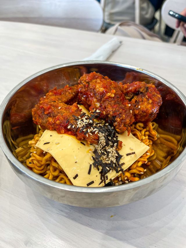 Spicy korean chicken, cheese and spicy ramen in a metal bowl