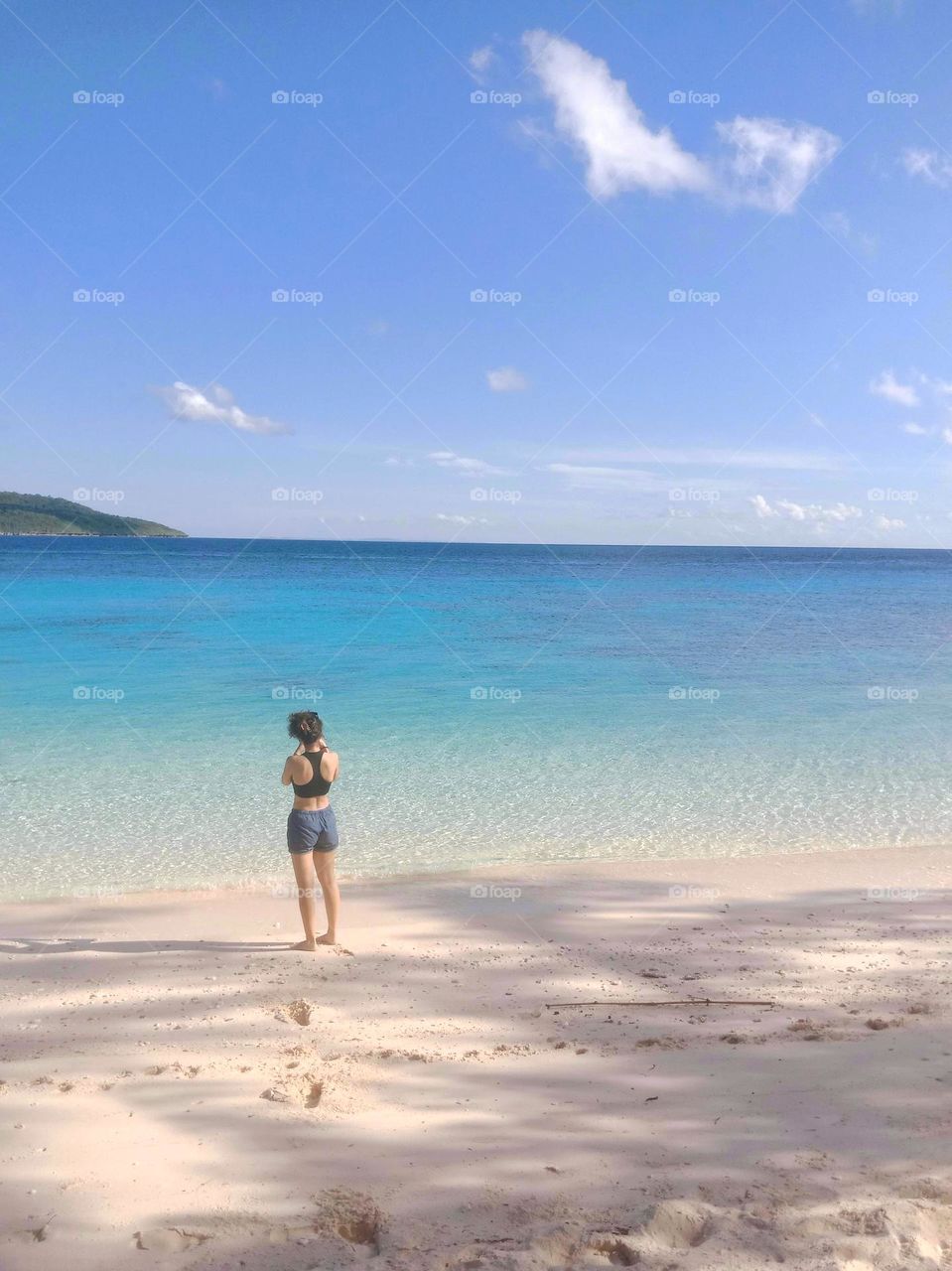 A girl enjoying the beauty of clear seawaters on a sunny day in a tropical island