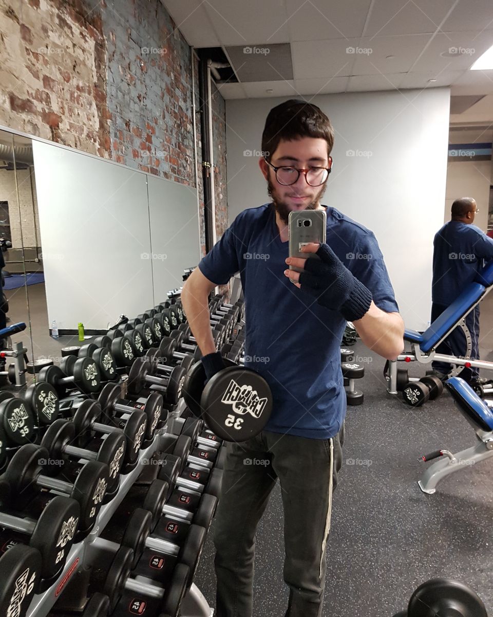 Young man holding mobile phone in hand in gym
