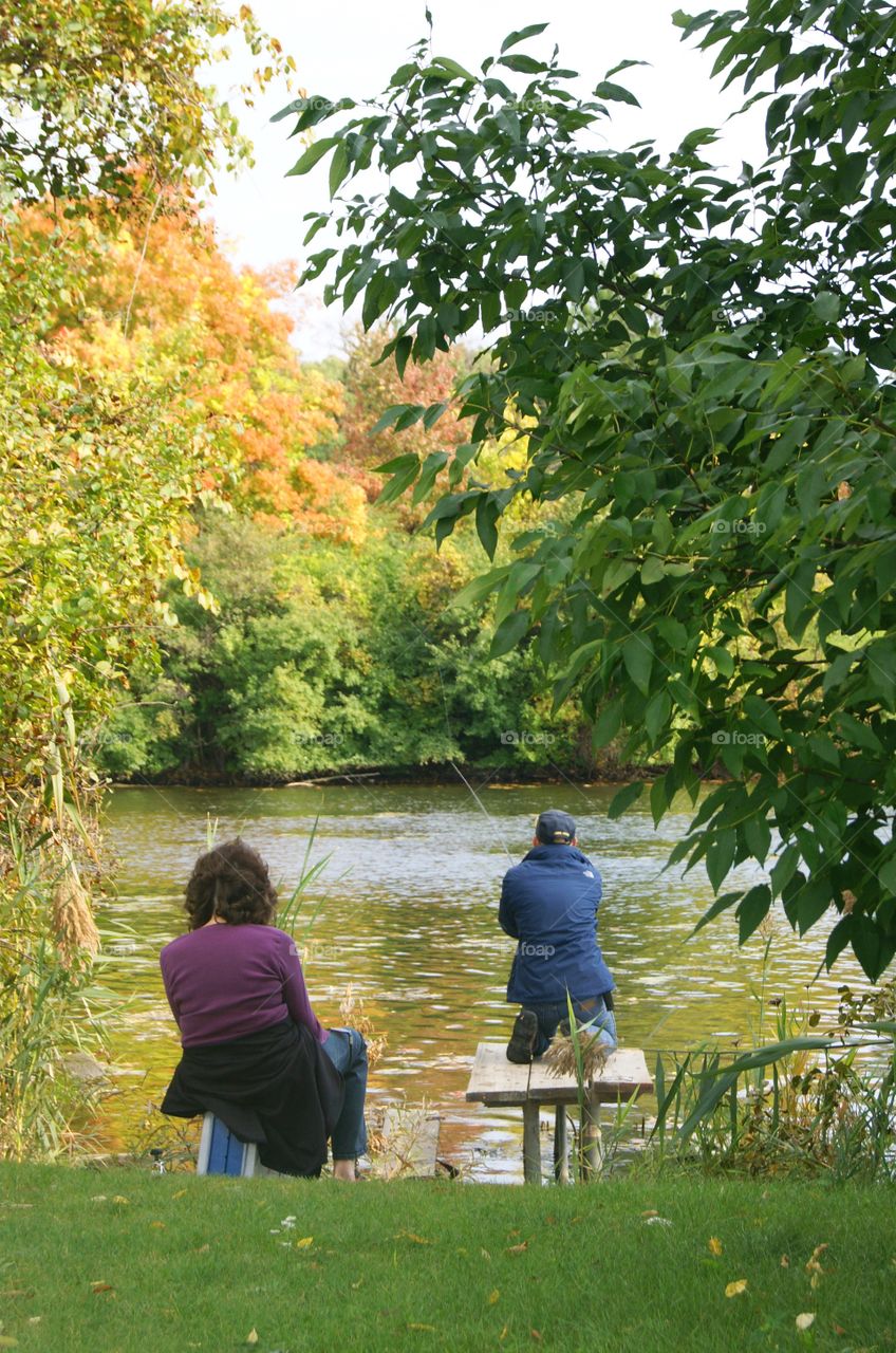 A husband fishing while the wife watches on a beautiful fall day in Michigan 