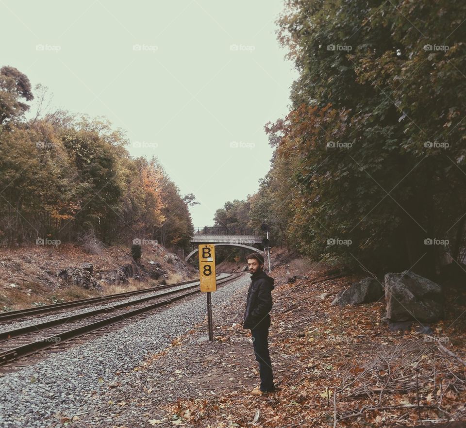 Young man standing near empty railroad