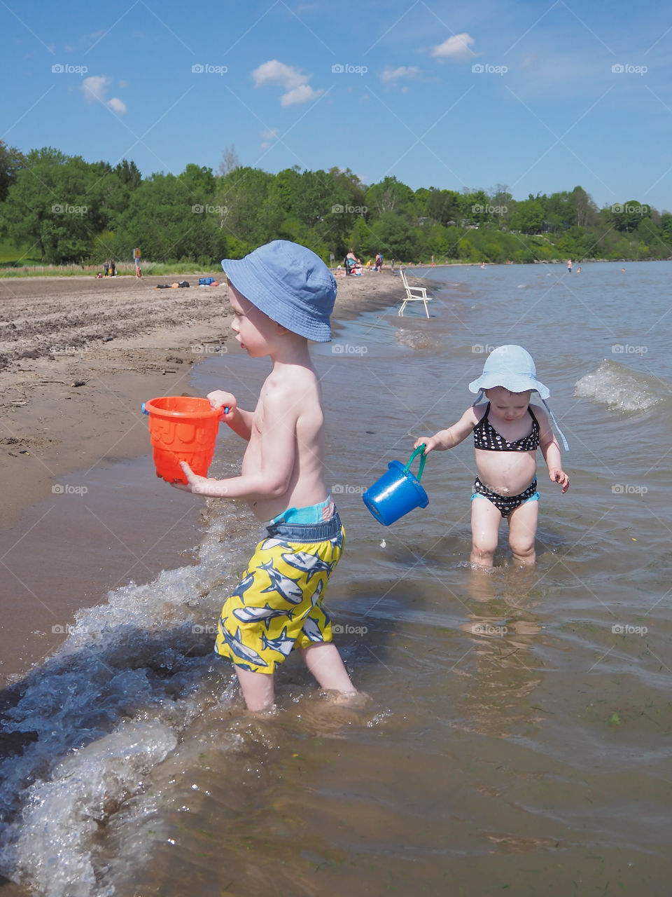 Brother & sister playing in the water at the beach shores of Port Burwell, Ontario, Canada.