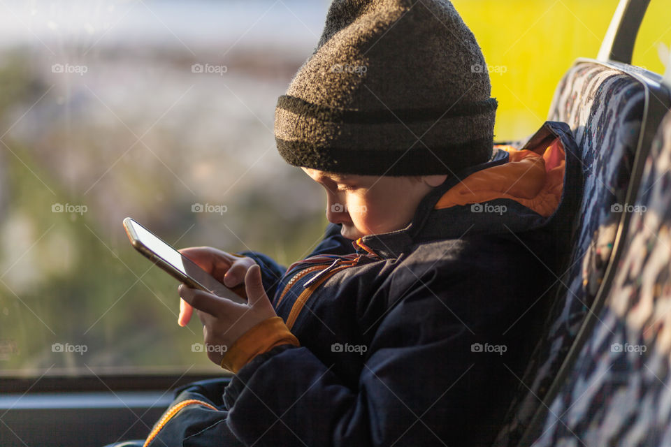 Boy with smart phone in bus. Preschool boy with smart phone in bus