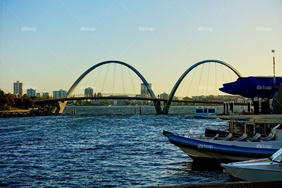 The Swan River view from Elizabeth Quay, Perth, Western Australia. Boat and ferry can be seen, and there is a bridge. On the opposite bank of the river, we can see many buildings which are used as residential or business area.