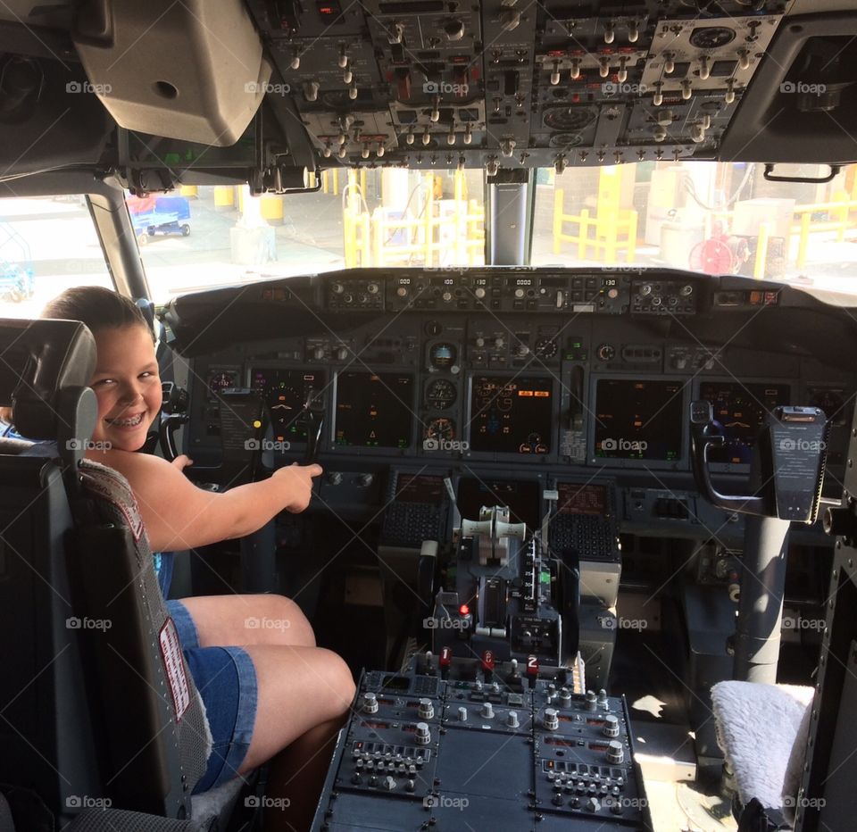 Girl sitting in pilot's seat of an airplane