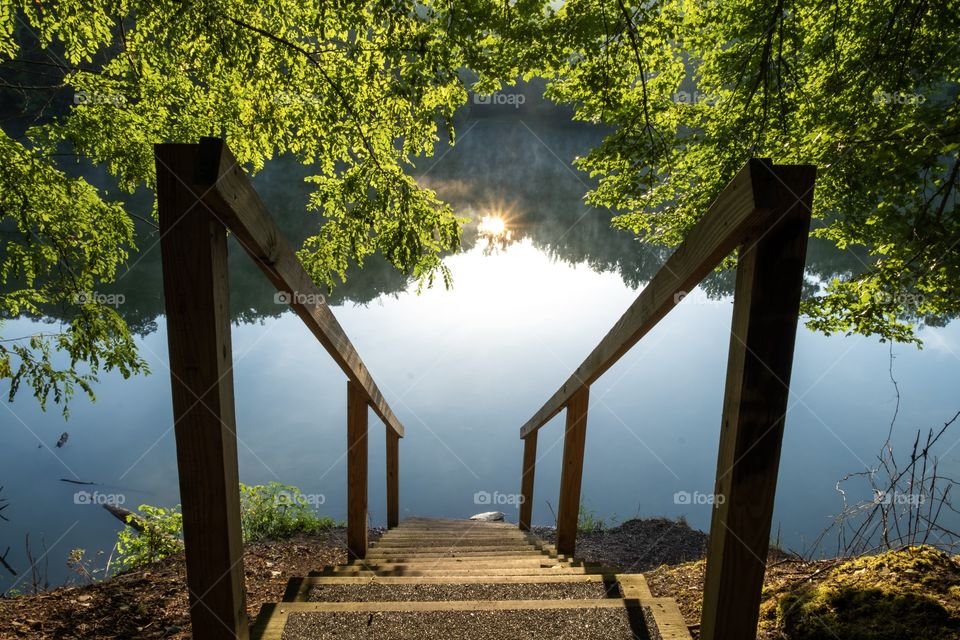The reflection of the early morning sun just peeking over the horizon viewed from the top of some stairs at Grundy Lakes Park, part of the South Cumberland State Park system, in Tracy City Tennessee. 