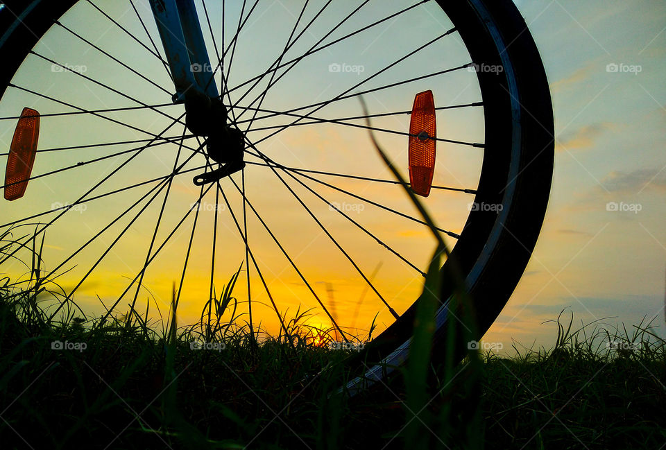 A bicycle wheel with a beautiful yellow sky background.