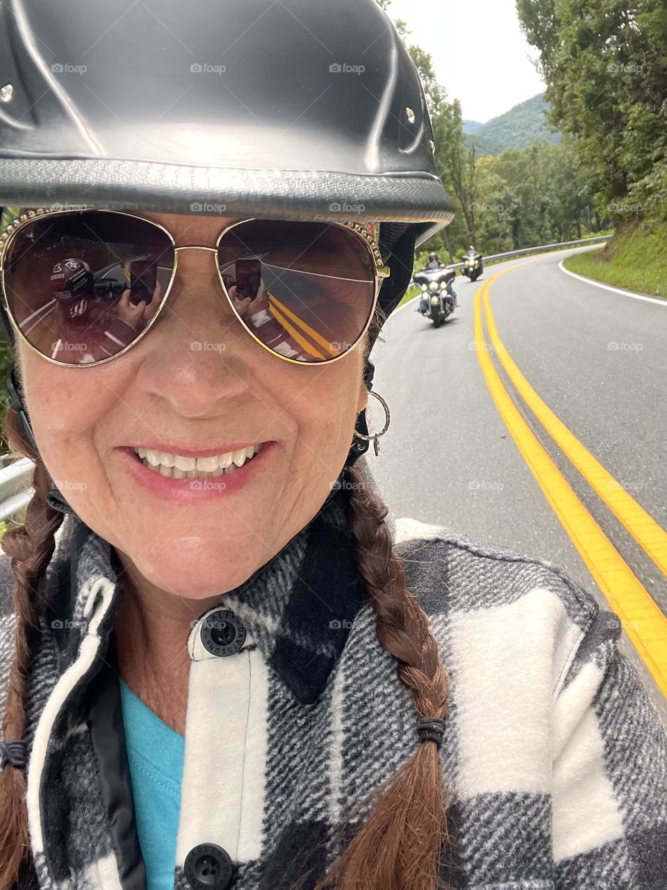 Woman riding on back of motorcycle with other motorcycles following behind on the roadway