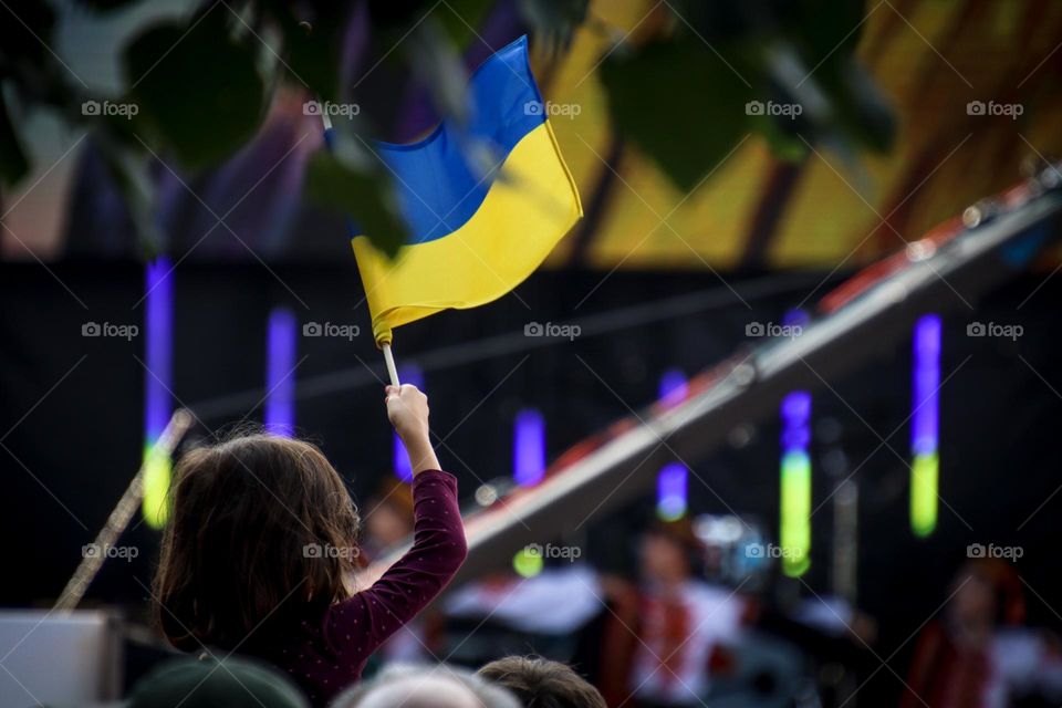 Girl is holding Ukrainian flag over the heads of the crowd