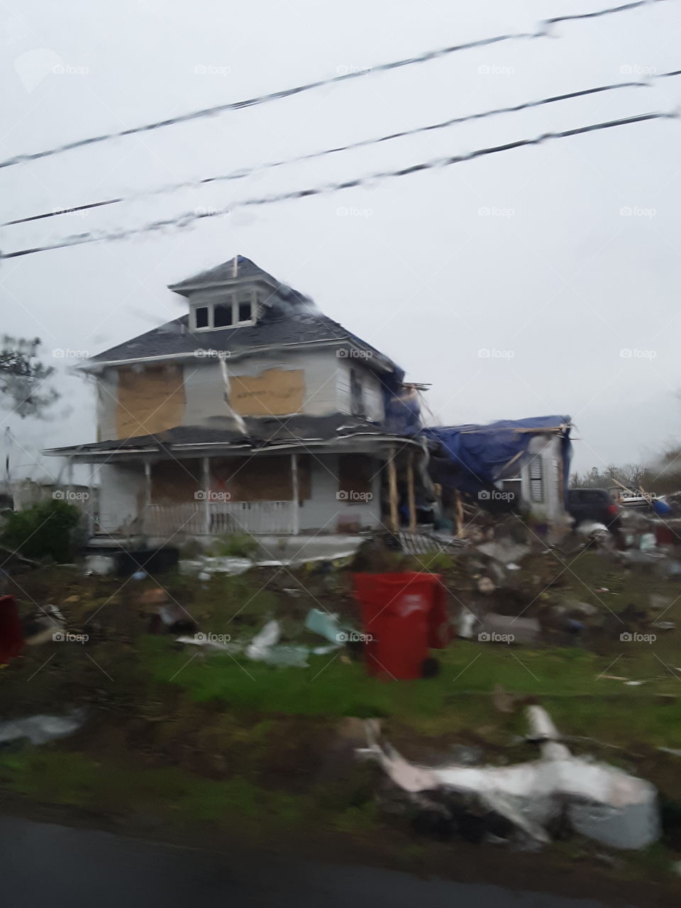 A house hit hard by a tornado, destroyed and abandoned, with trash and peices of rubble thrown about.