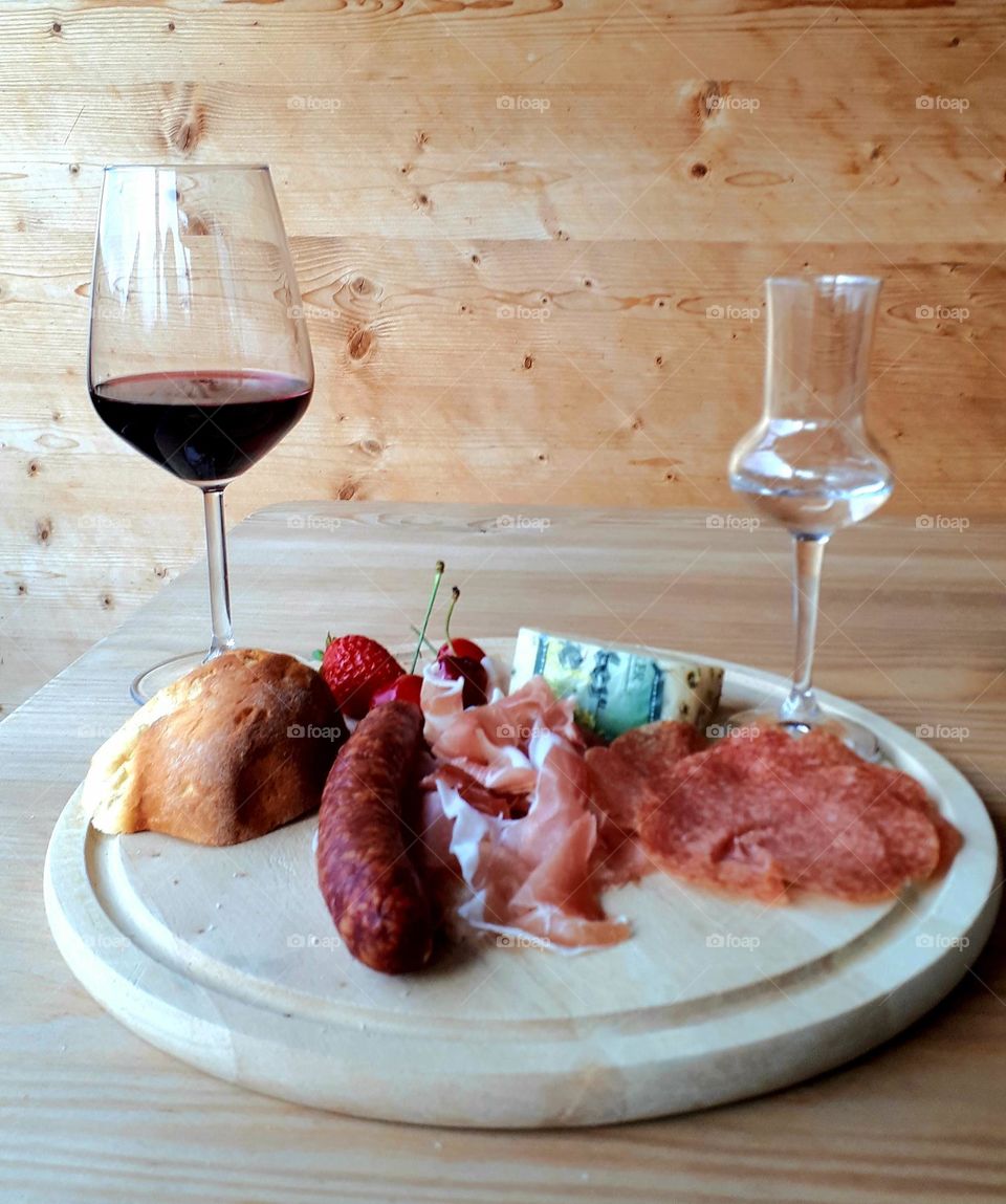 A typical south tyrol snack with red wine, sausages, chees  smoked bacon, salami and liquor
